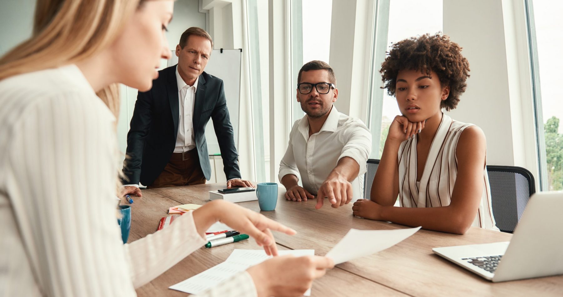 Business meeting. Group of young business people looking at documents and discussing something while sitting at the office table. Brainstorming