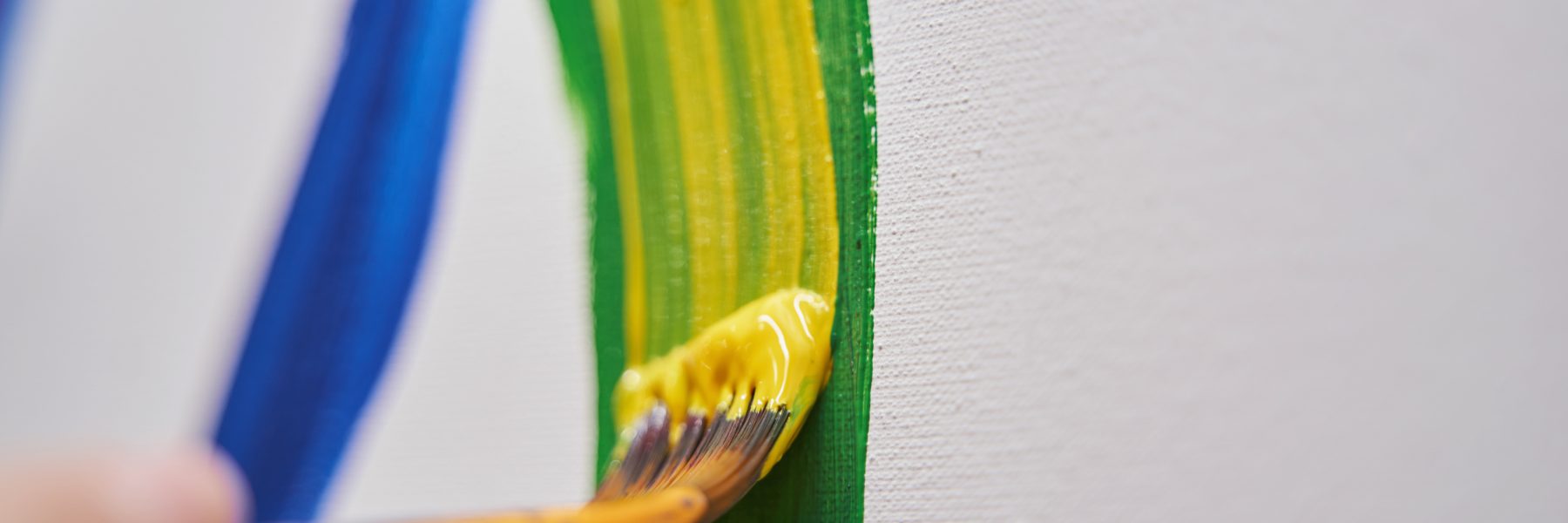 Professional art brush being in female hand while painting on canvas